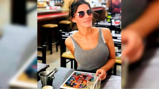 Natacha Jaitt sonríe con su tablet sobre la mesa de un restaurante.